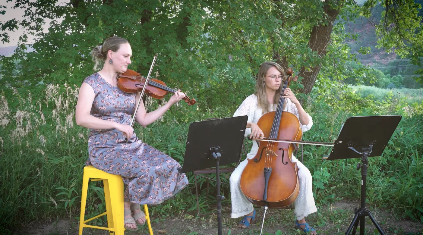 Annie and cellist performing outdoors at an event