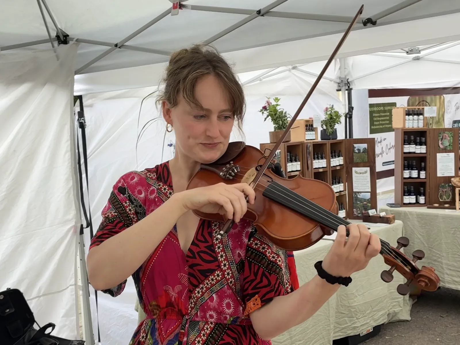 Annie playing violin under a tent at a Telluride market